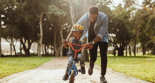 a man and his child learning how to ride a bike