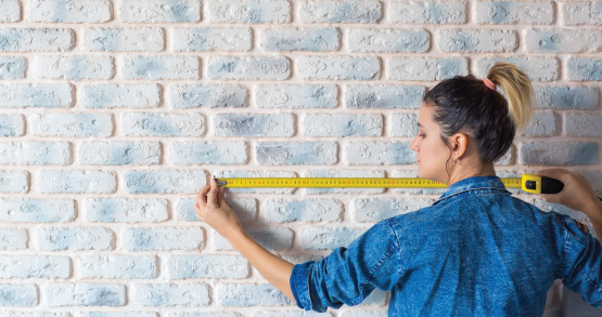 a woman measuring a wall